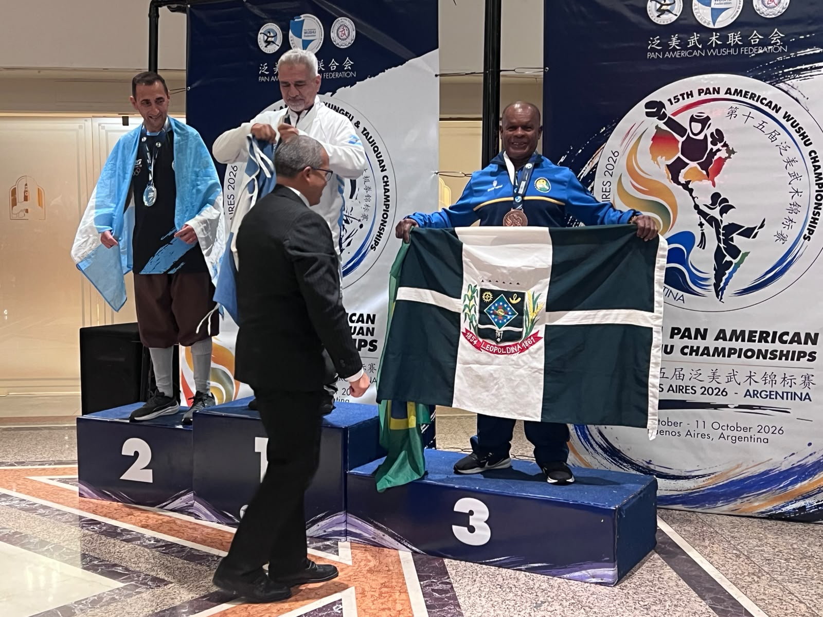 Mestre Betinho no terceiro lugar do pódio, com a bandeira de Leopoldina